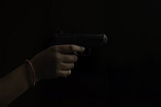 a hand holding a gun in the dark