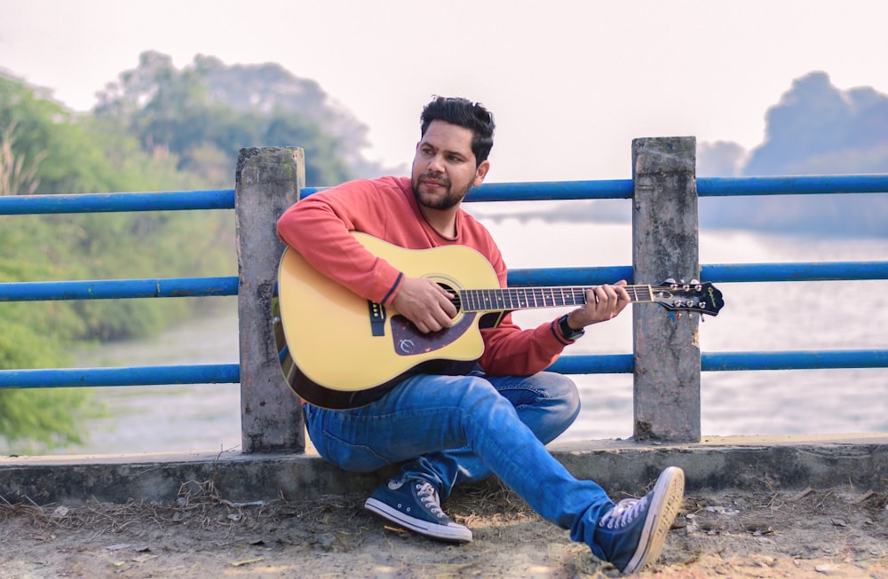 a man sitting on the ground playing a guitar