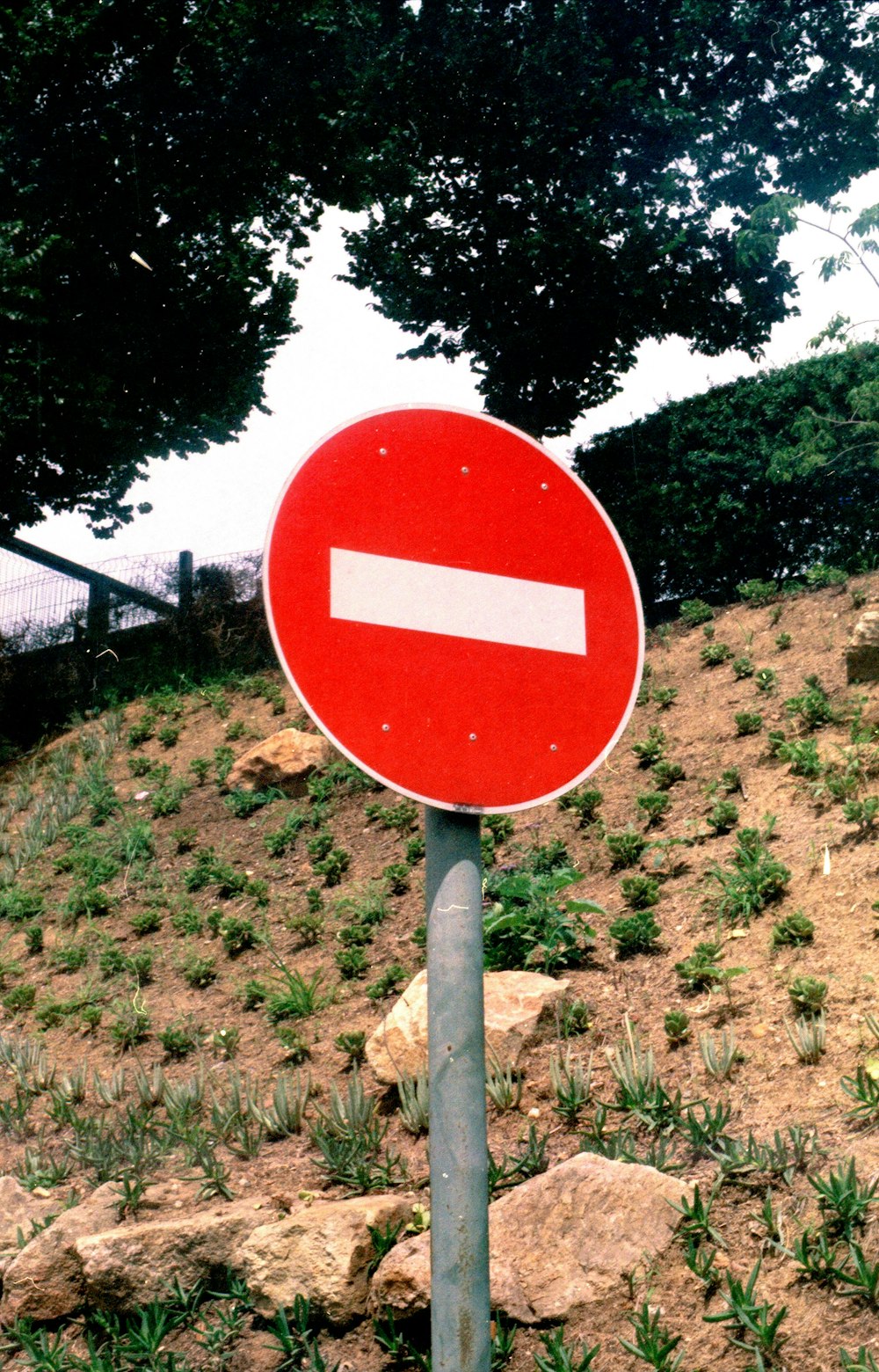 a red and white sign sitting on the side of a hill