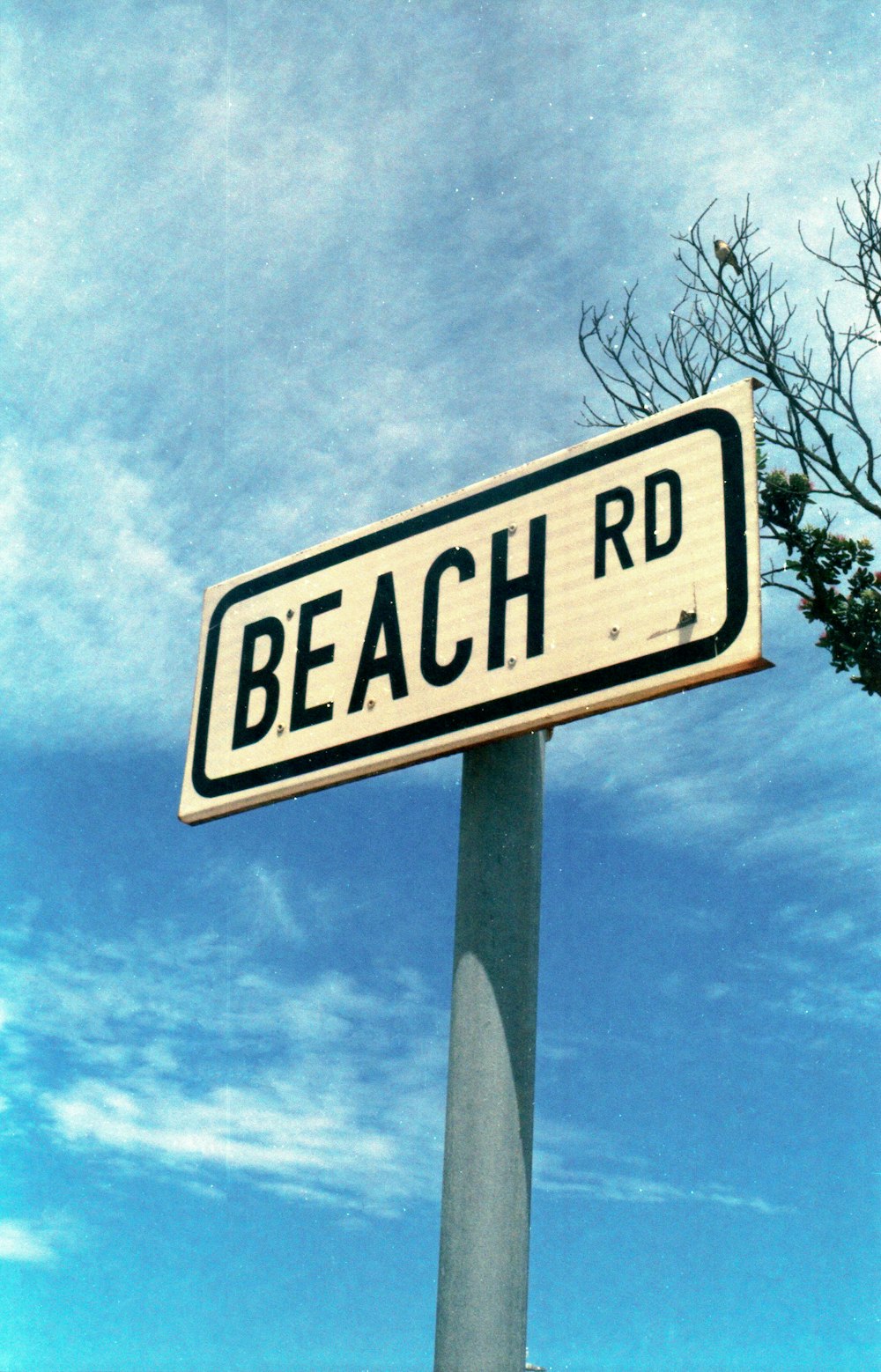 a white and black street sign sitting on top of a metal pole