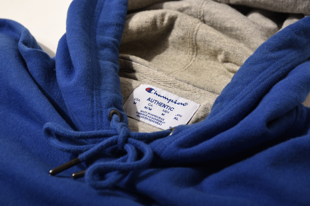 a close up of a blue hoodie with a tag on it