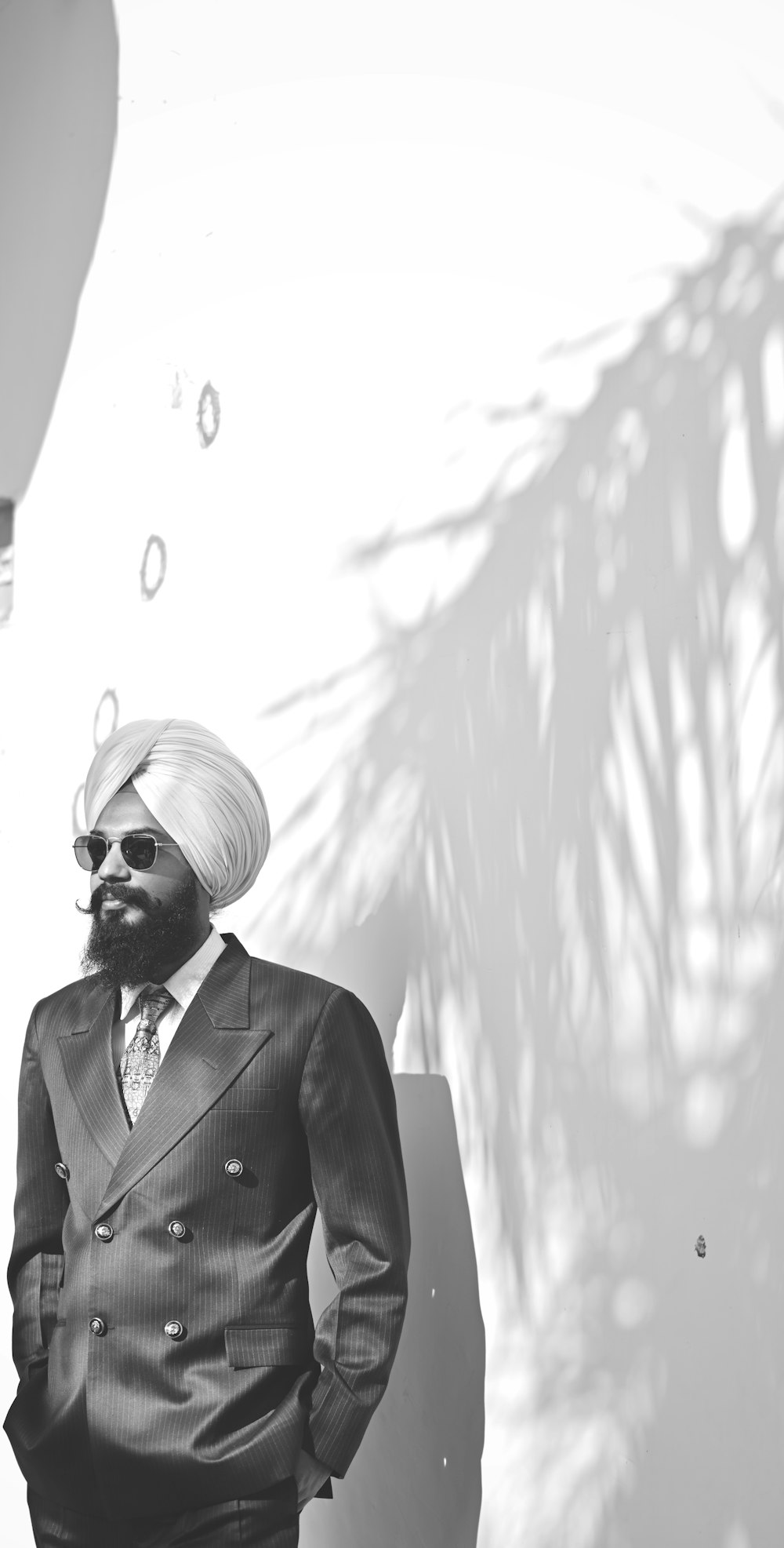 a man in a turban and sunglasses standing in front of a palm tree