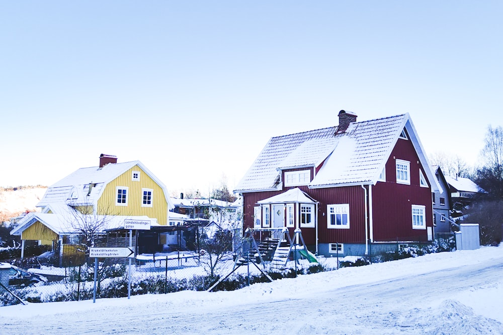 uma casa vermelha e amarela com neve no chão