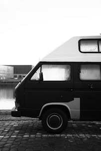 Hexagonal framed photo of a sleek white Hiace van parked near a mosque, bathed in soft morning light.