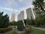 a statue in a park with tall buildings in the background