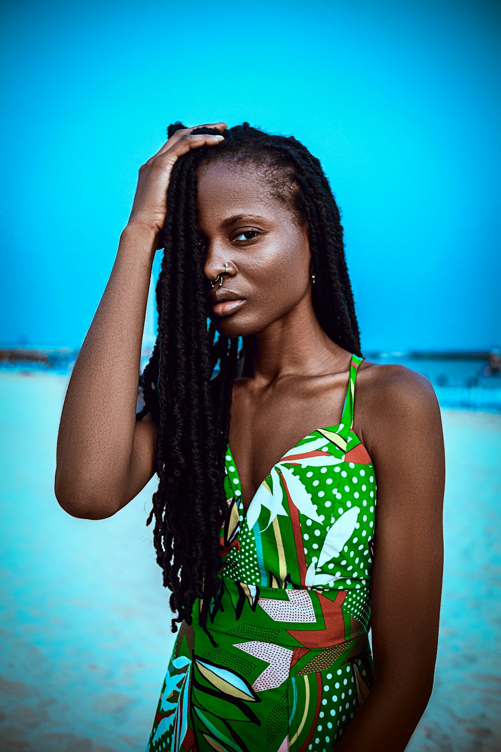 a woman in a green and white one piece swimsuit standing on a beach