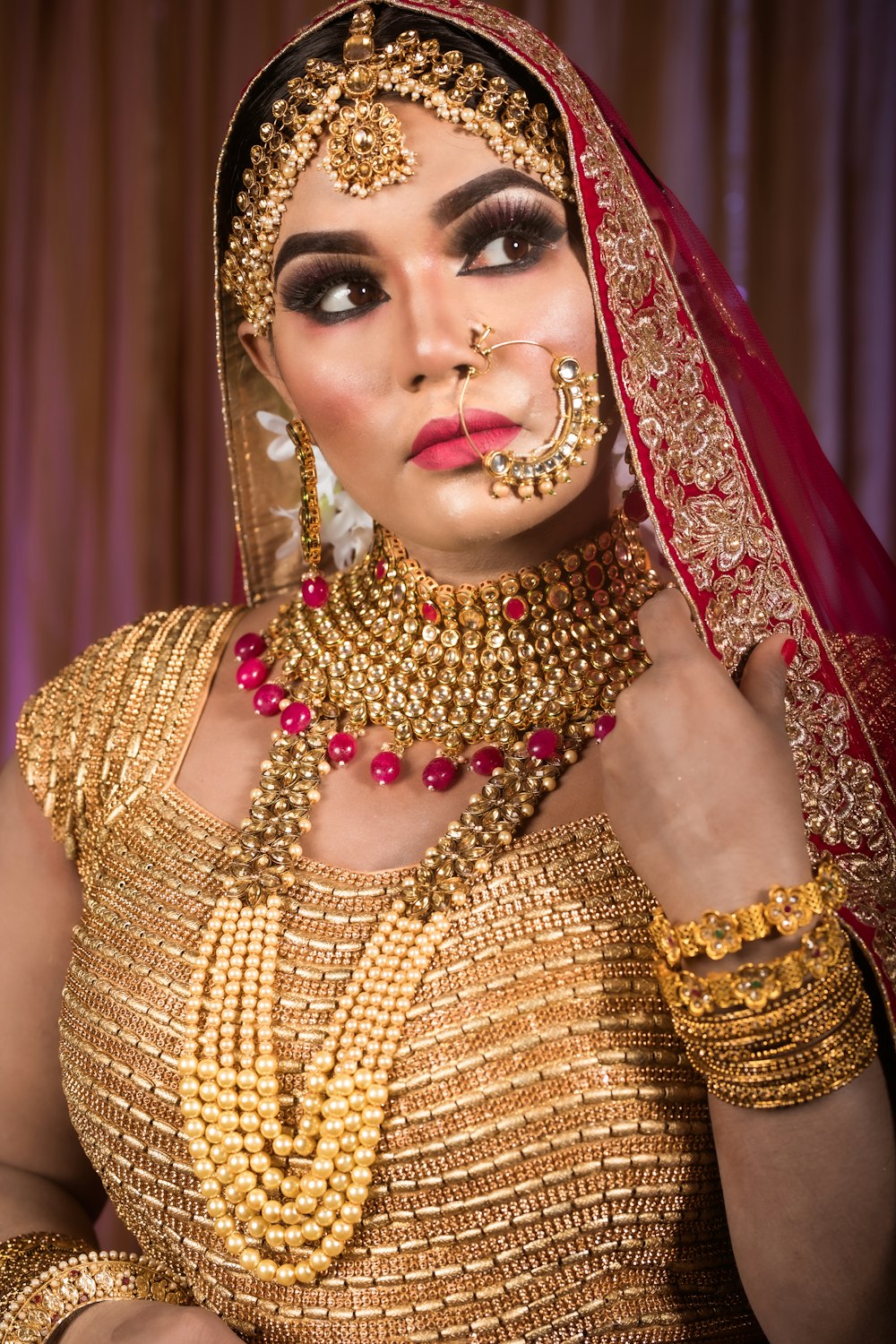 a woman wearing a gold and red bridal outfit