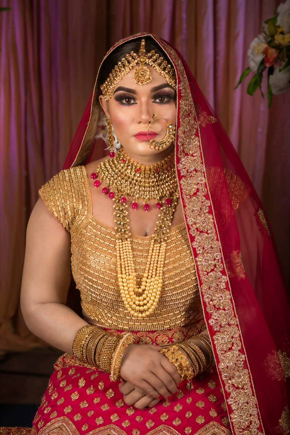 a woman in a red and gold bridal outfit