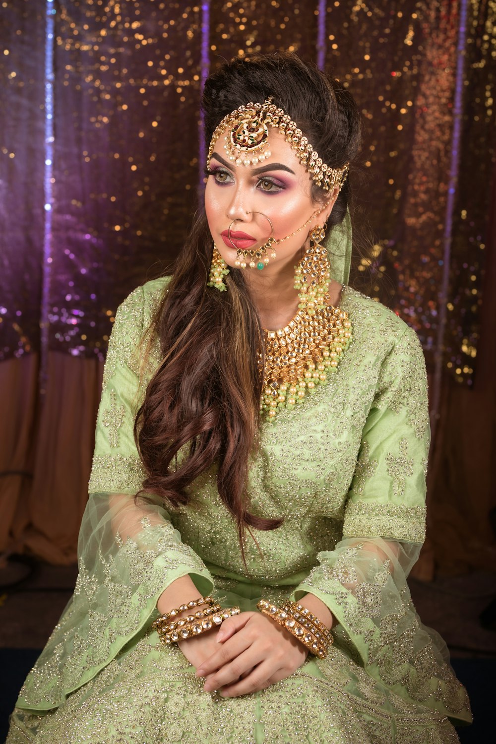 a woman wearing a green outfit and jewelry