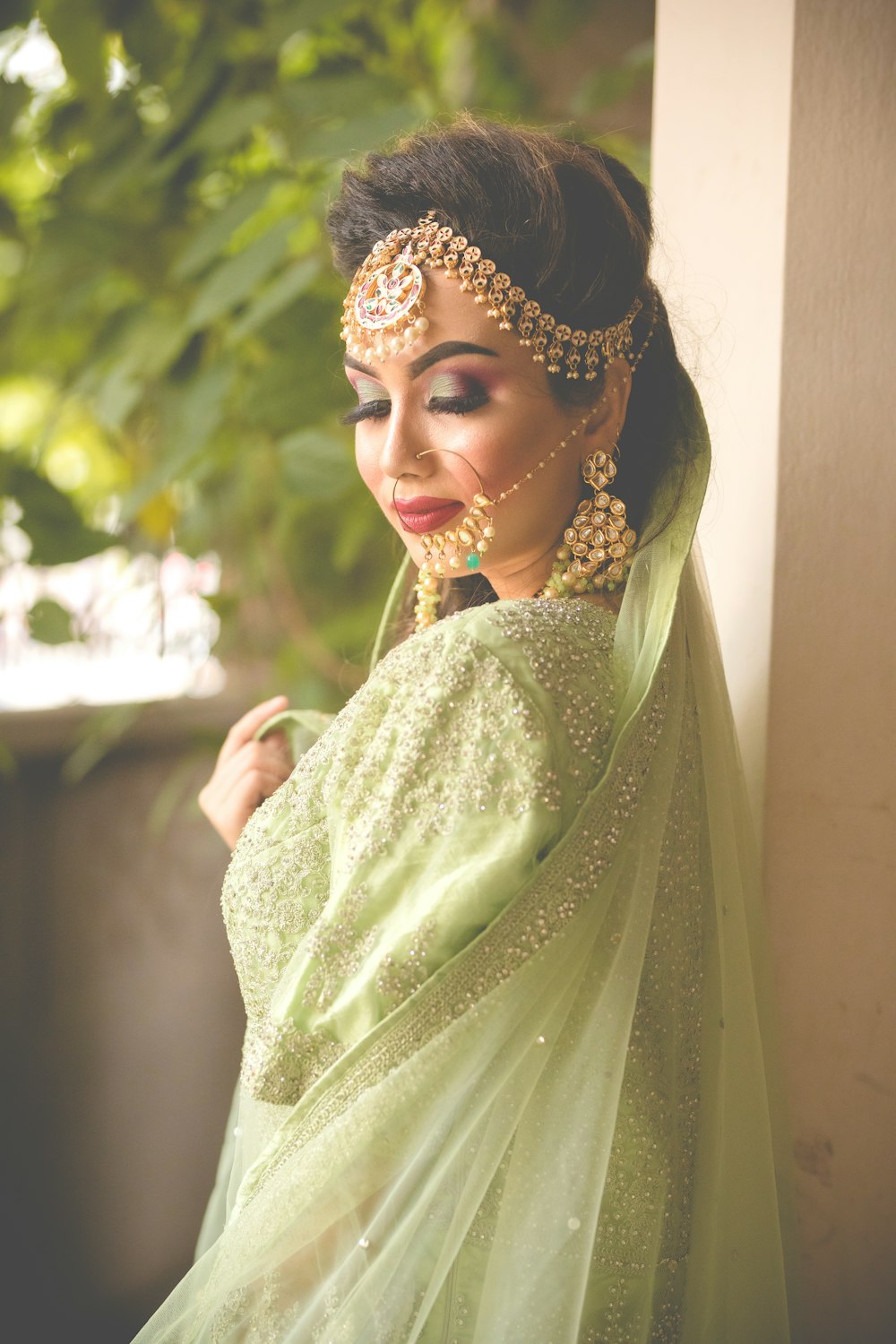 a woman in a green outfit with a veil on her head