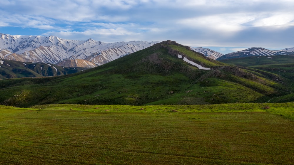 a large grassy field with mountains in the background