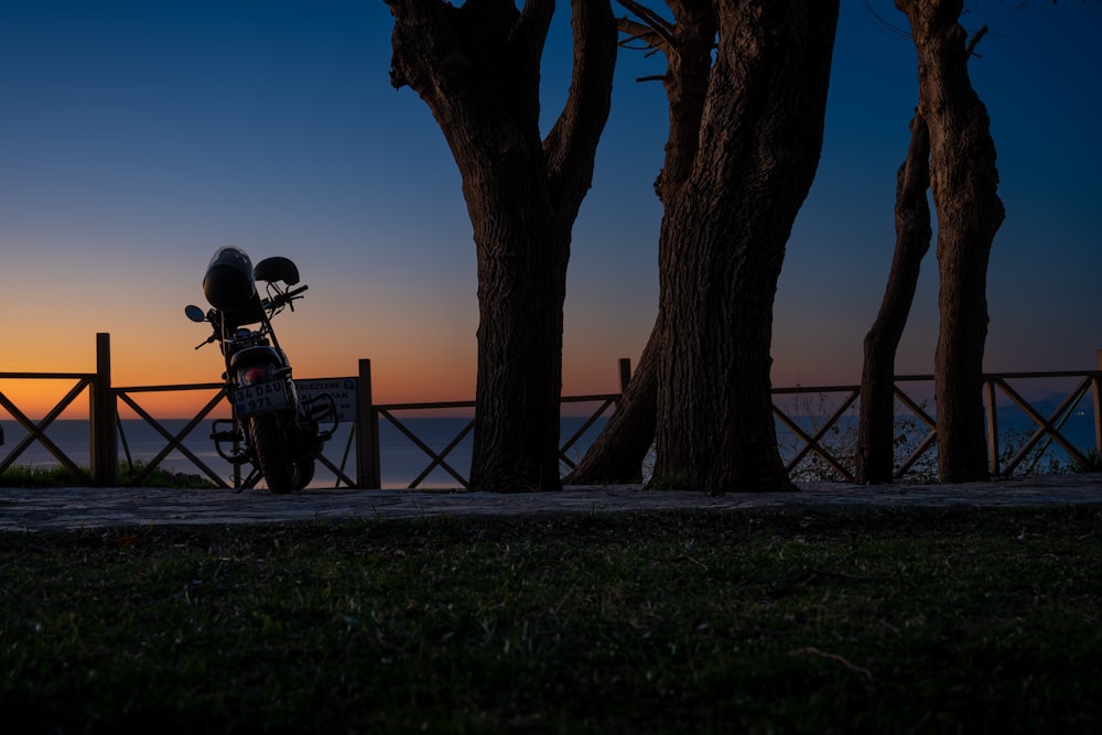 a motorcycle parked next to some trees at sunset