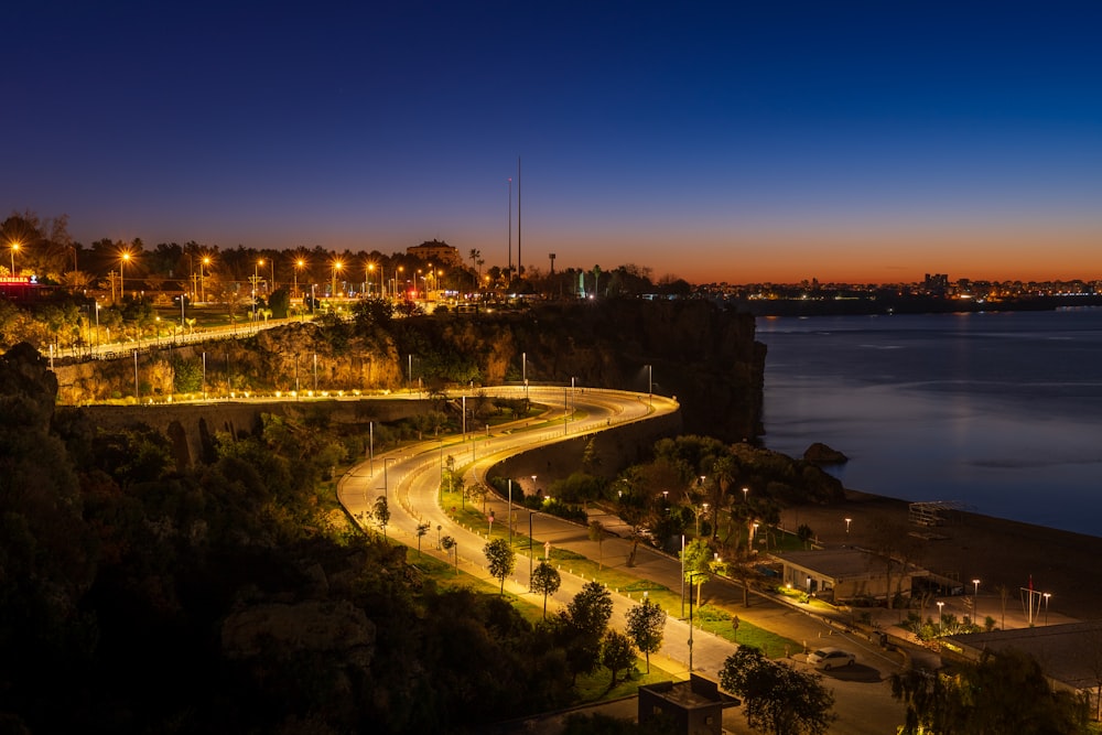 a night time view of a road near a body of water