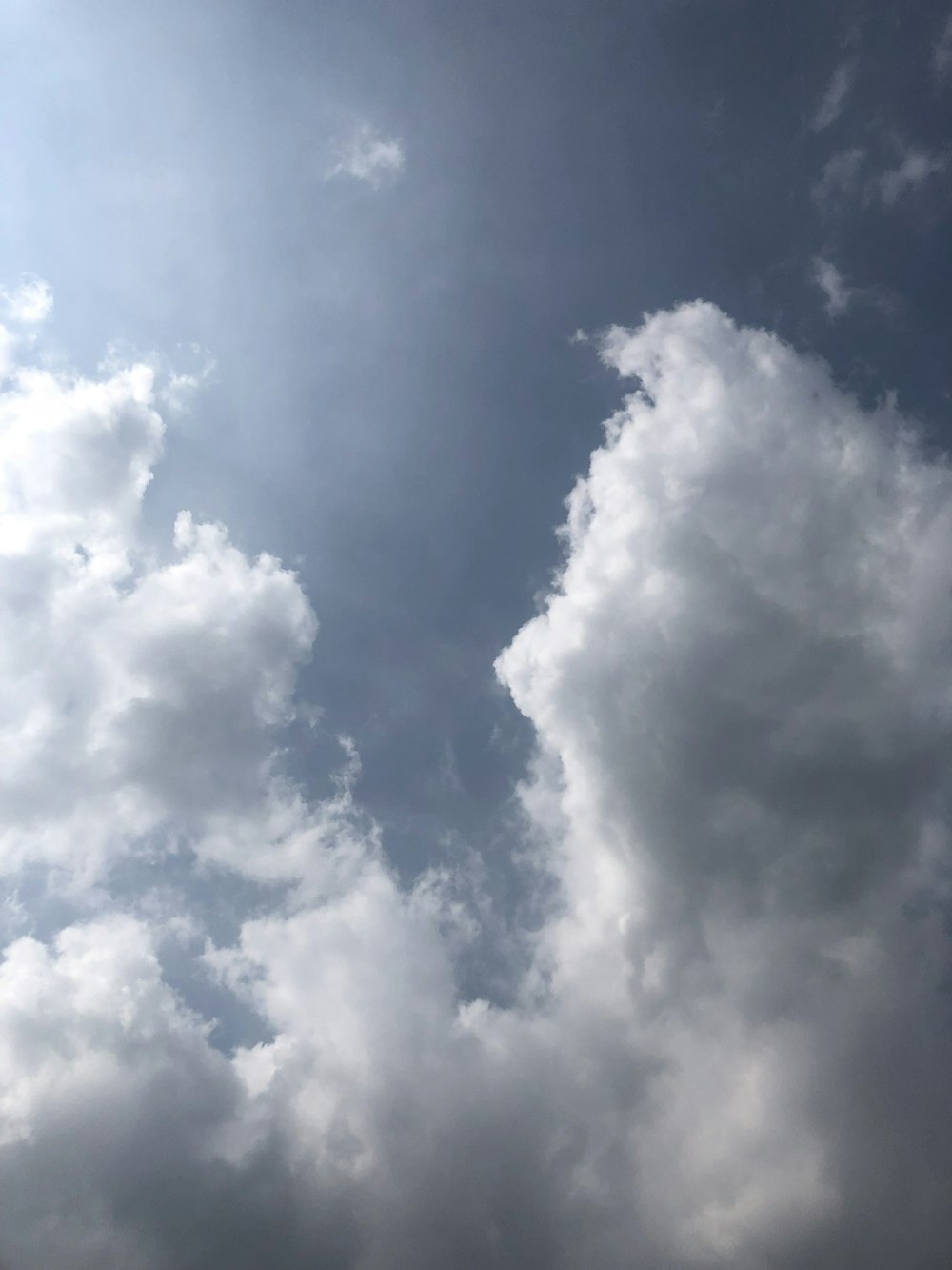 a plane flying through a cloudy blue sky