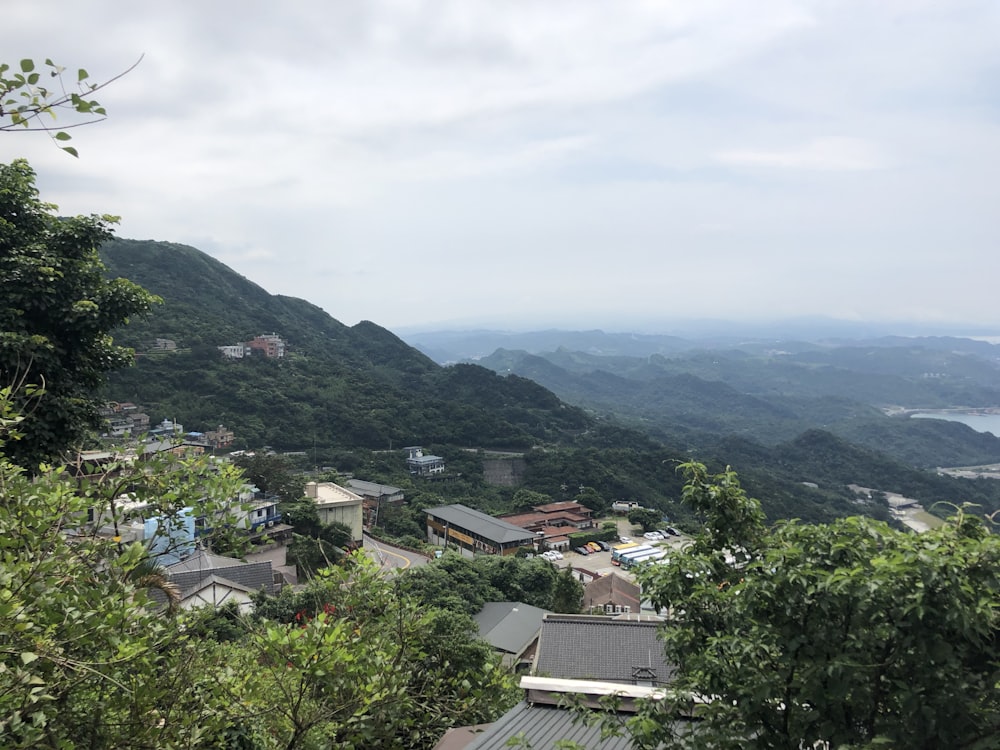 a scenic view of a mountain town with a body of water in the distance