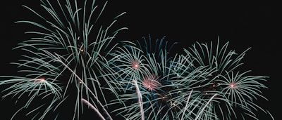 A sequence of fireworks bursting in vibrant neon green arcs over a dark horizon.