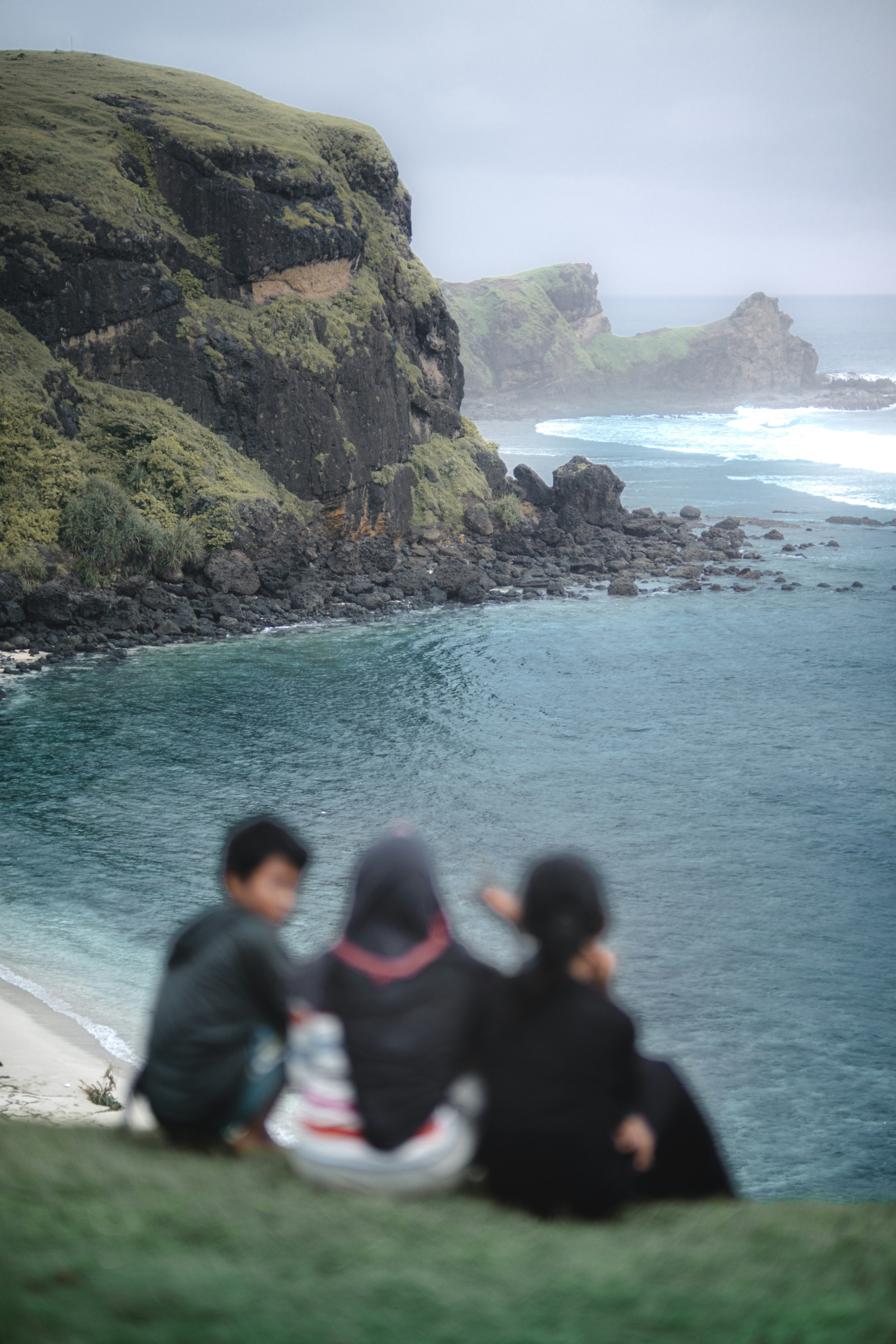 A group of people sitting on top of a lush green hillside photo – Free ...