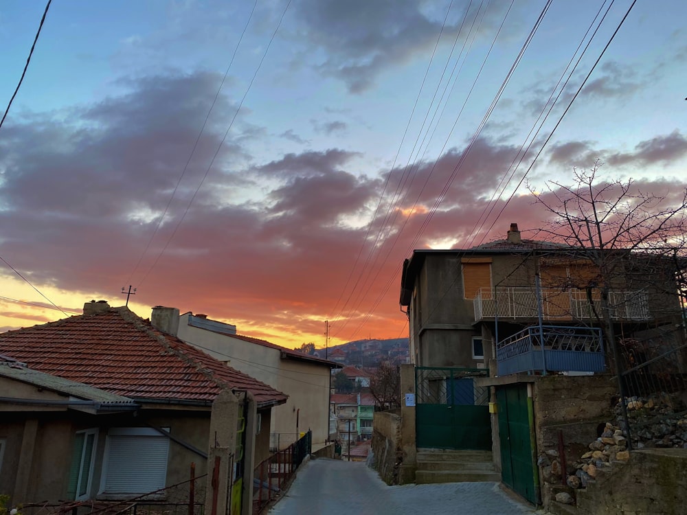a sunset view of a street with houses and a hill in the background
