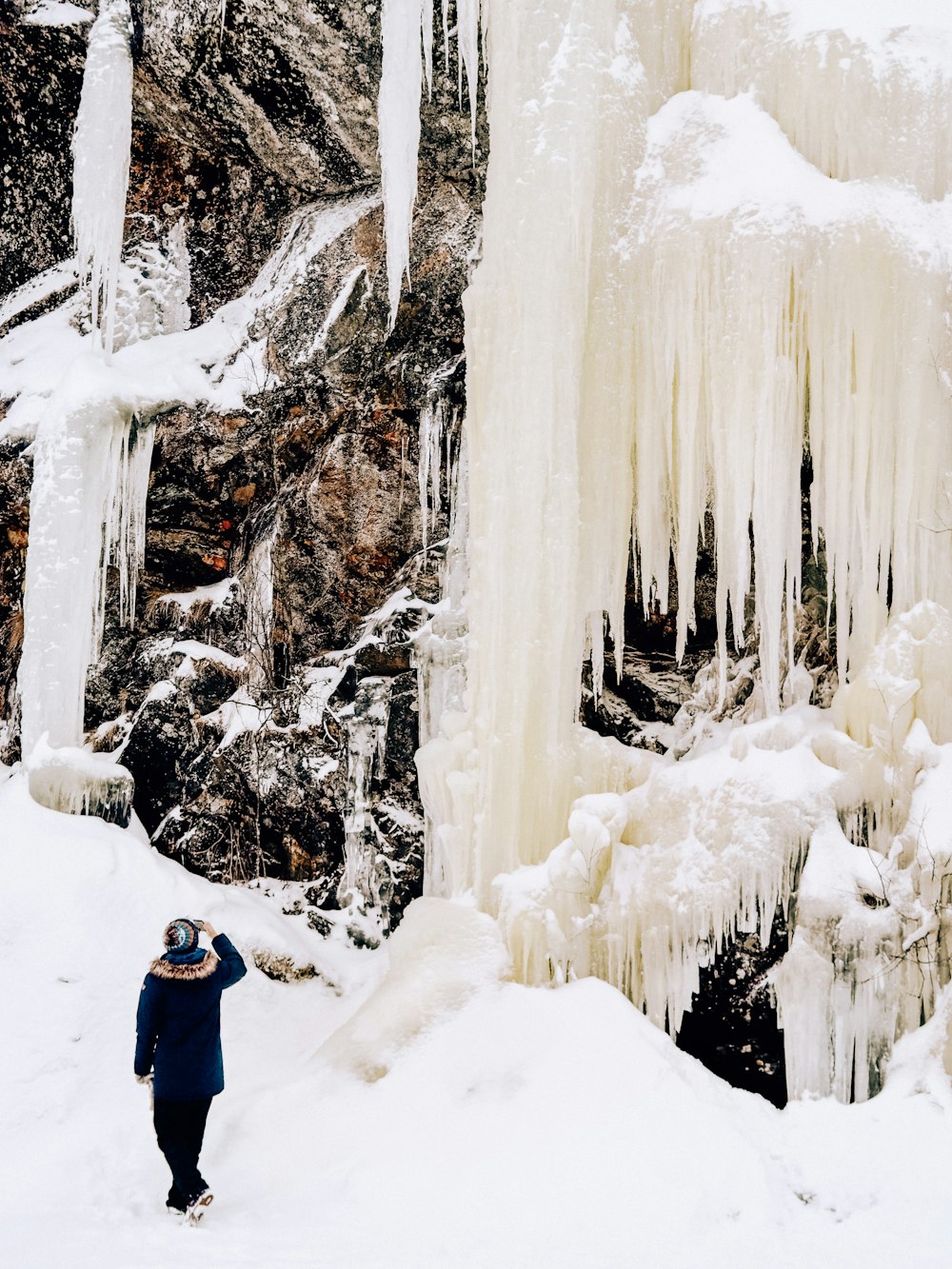 a person standing in front of a frozen waterfall
