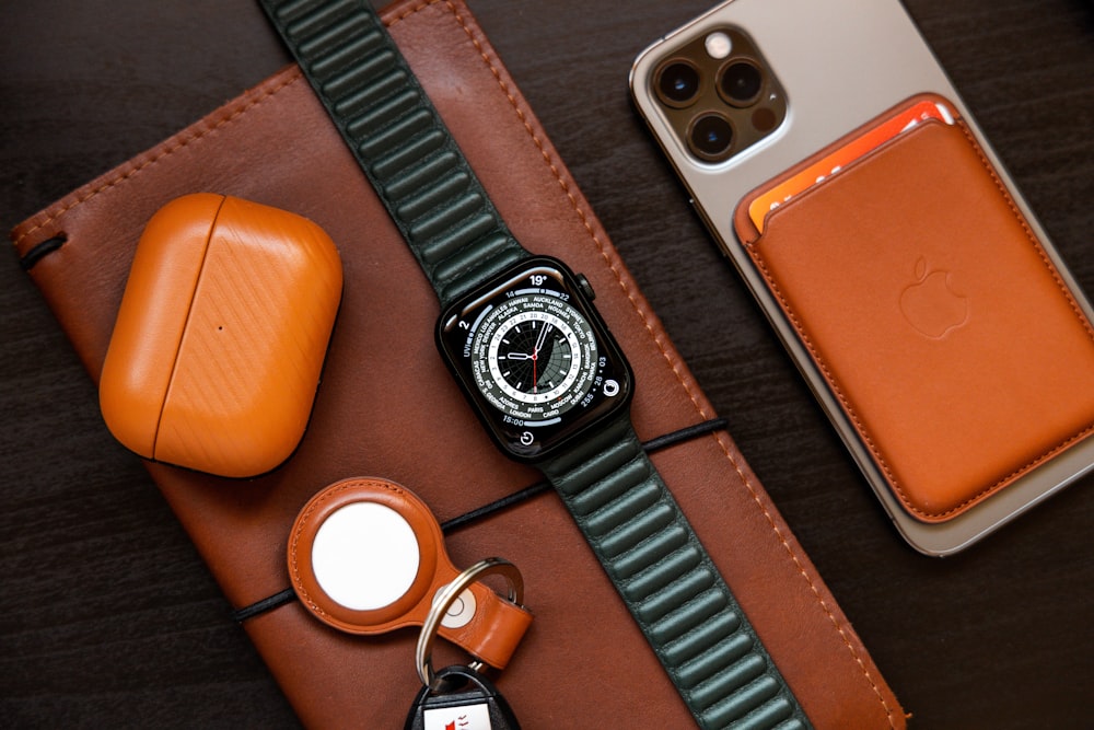 a cell phone, a watch, and a leather case on a table