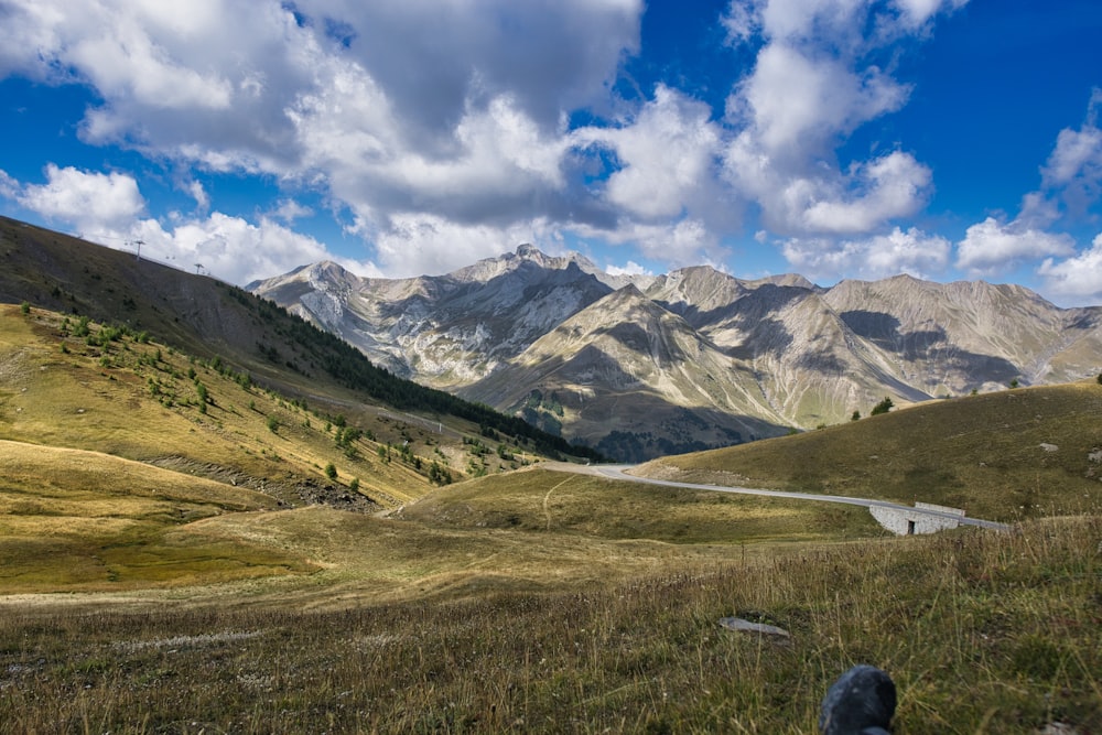 a scenic view of a mountain range with a winding road in the foreground