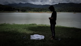 A contemplative person meditating by a tranquil lake.