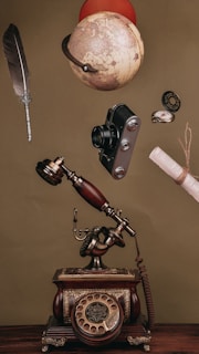 an old fashioned phone with a telescope and other items above it