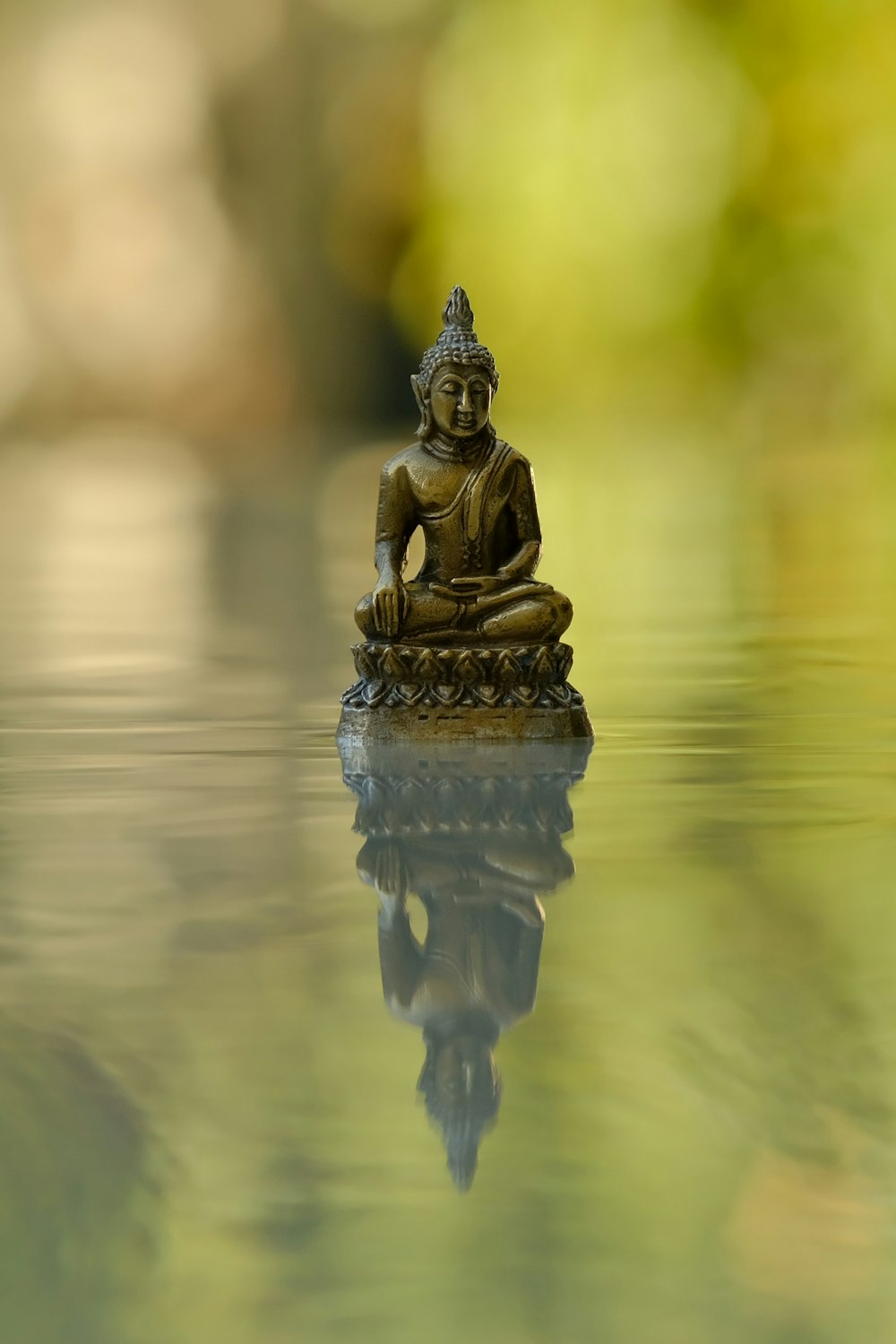 a small buddha statue sitting on top of a body of water