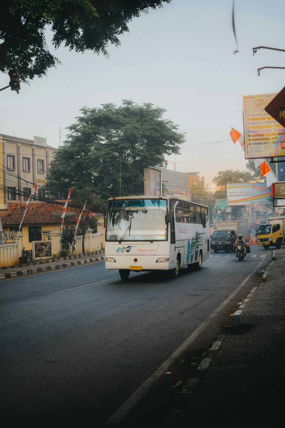 a white bus driving down a street next to tall buildings