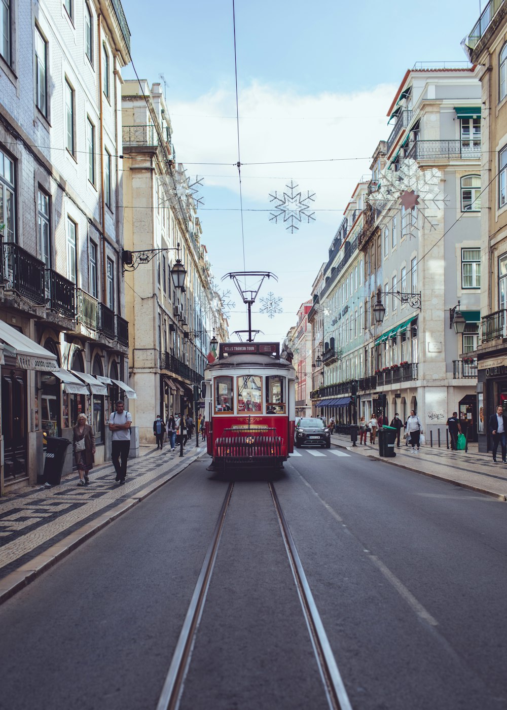 Ein roter Straßenbahnwagen fährt eine Straße neben hohen Gebäuden entlang