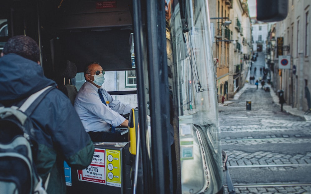 a man wearing a face mask sitting in a bus