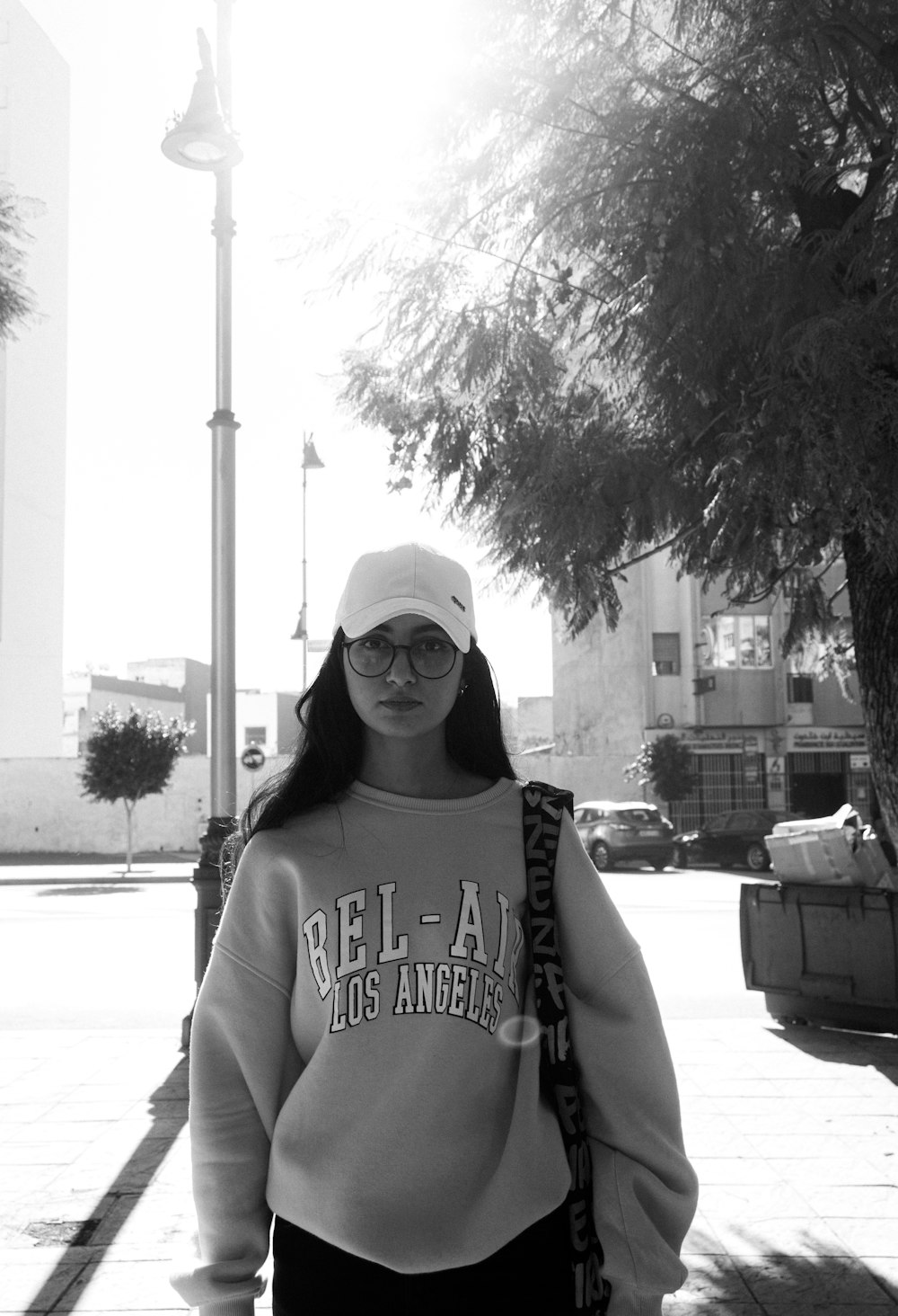 a woman walking down a sidewalk wearing a sweatshirt