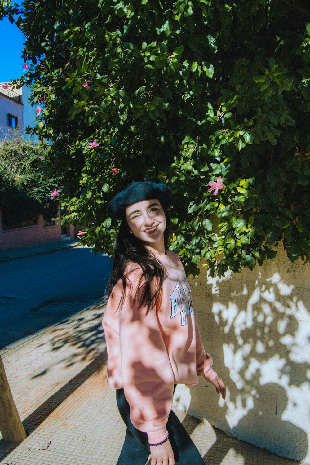 a woman standing next to a tree with a hat on