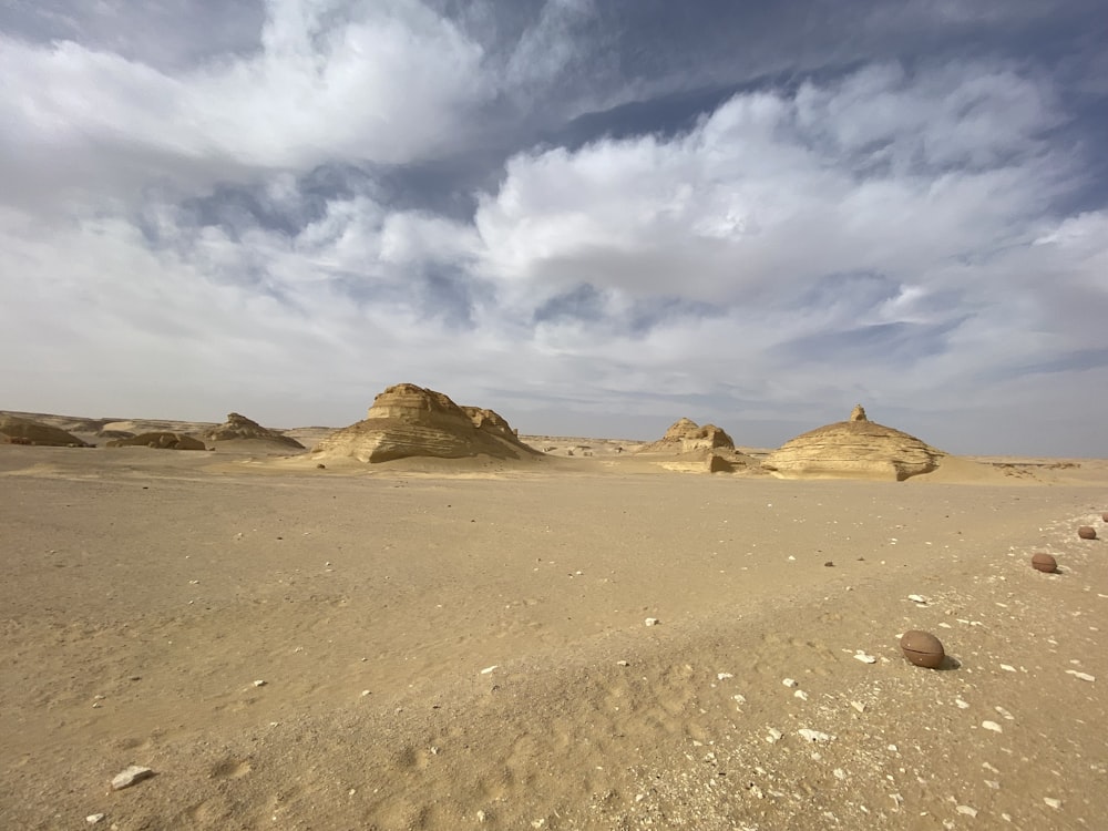 a desert landscape with rocks and sand under a cloudy sky