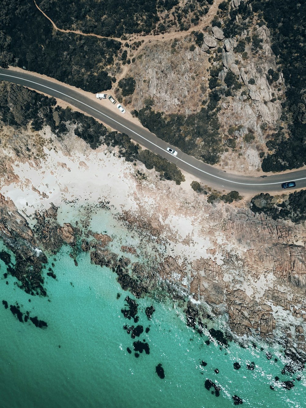 an aerial view of a road near a body of water