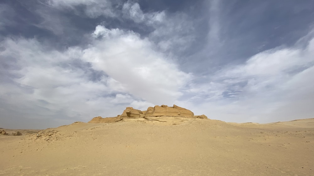 a desert landscape with sand dunes and clouds