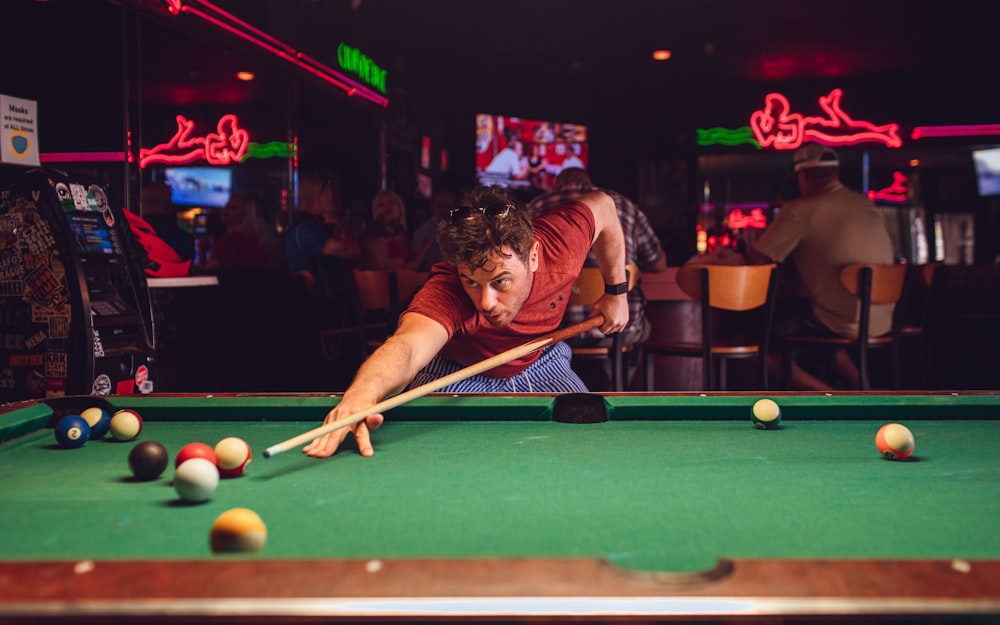 a man leaning over a pool table to hit a ball