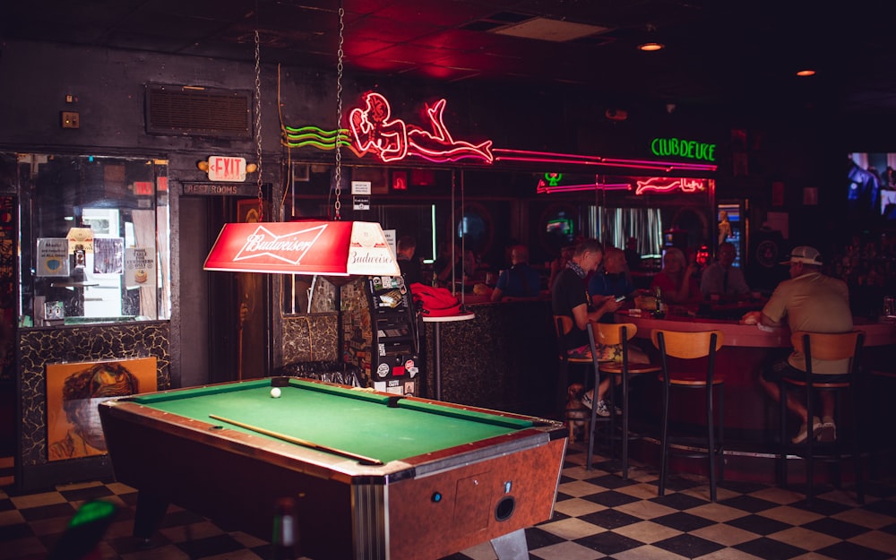a pool table in a bar with neon signs