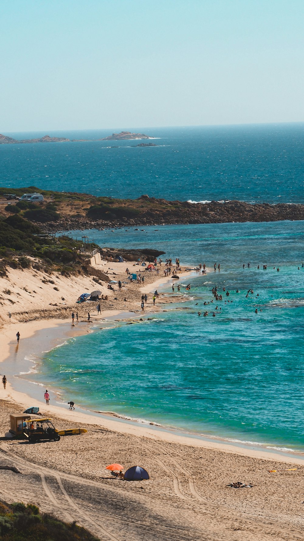 a group of people standing on top of a sandy beach