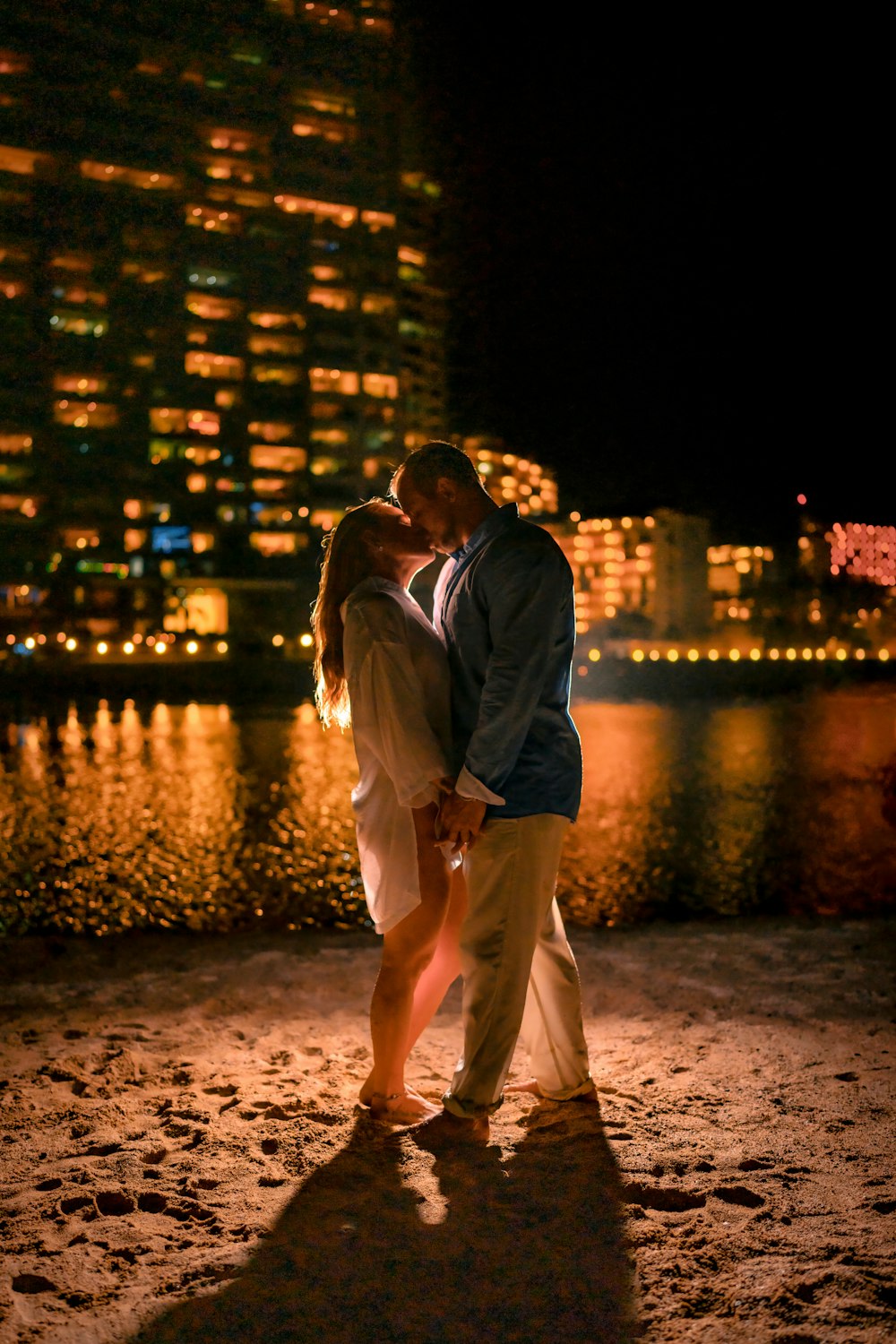 a couple kissing on the beach at night
