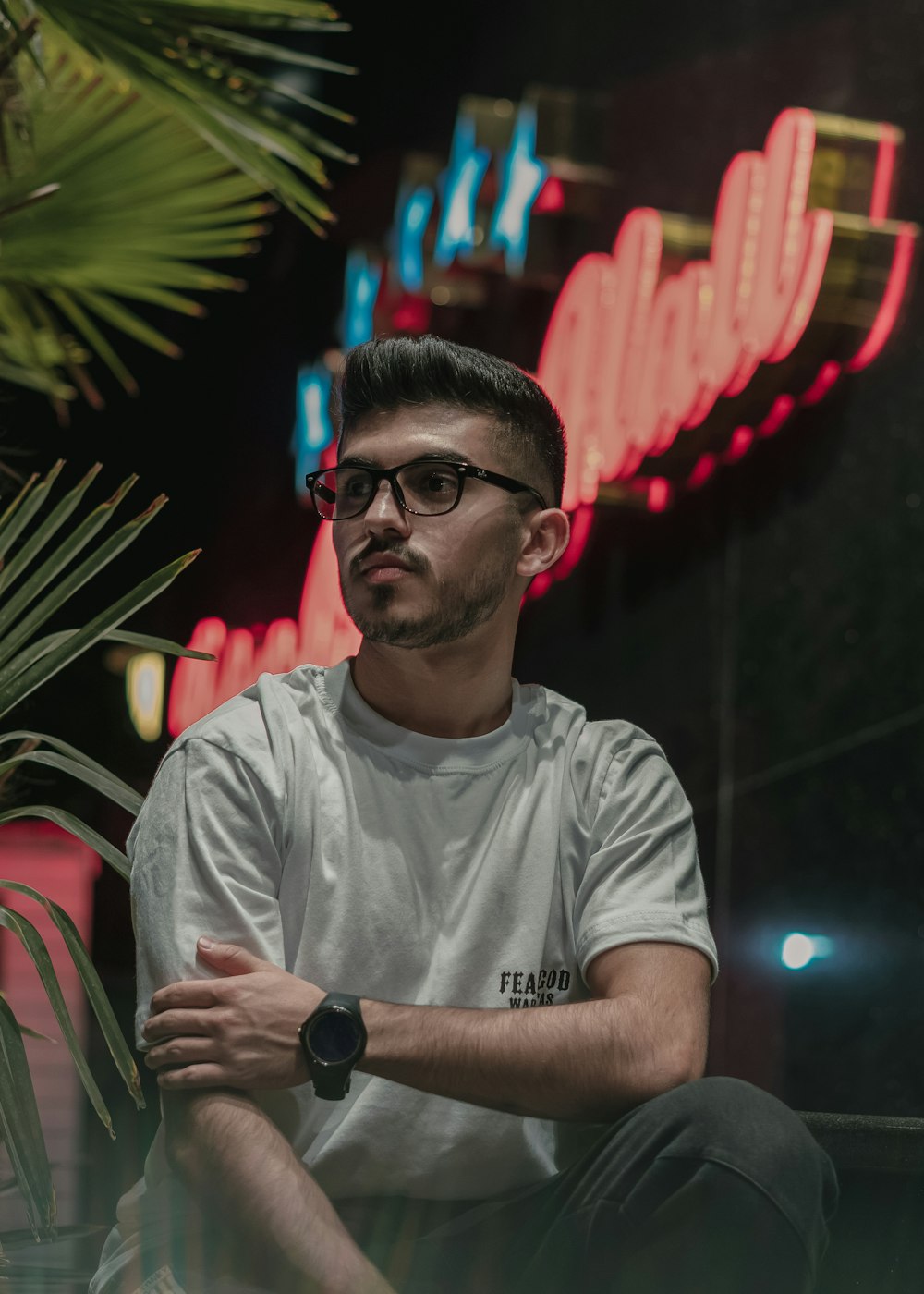 a man sitting in front of a neon sign