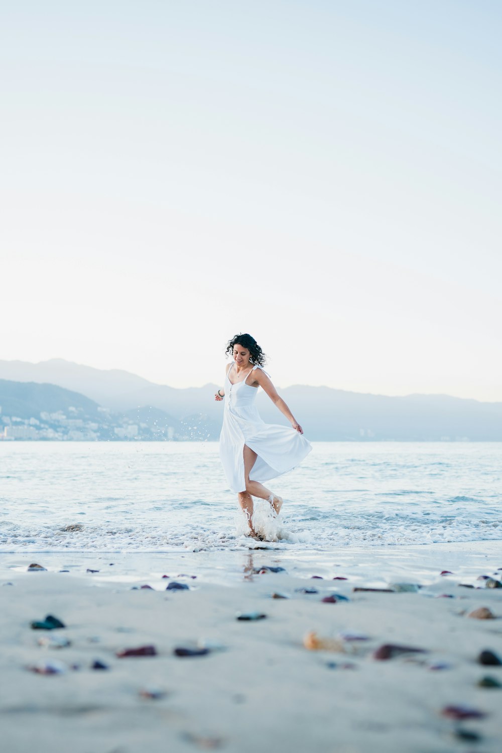 a woman in a white dress running on the beach