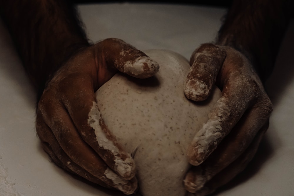 a pair of hands holding a ball of dough