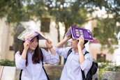 Group of smiling students in white coats holding textbooks on campus lawn.