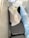 A tightly packed freezer contains several objects wrapped in plastic bags. One of the bags is white with a black lining and tied with a yellow tie. A gloved hand is visible resting on the package. The surrounding bags have varying shades, including blue.