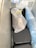 A tightly packed freezer contains several objects wrapped in plastic bags. One of the bags is white with a black lining and tied with a yellow tie. A gloved hand is visible resting on the package. The surrounding bags have varying shades, including blue.
