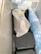 A tightly packed freezer contains several objects wrapped in plastic bags. One of the bags is white with a black lining and tied with a yellow tie. A gloved hand is visible resting on the package. The surrounding bags have varying shades, including blue.