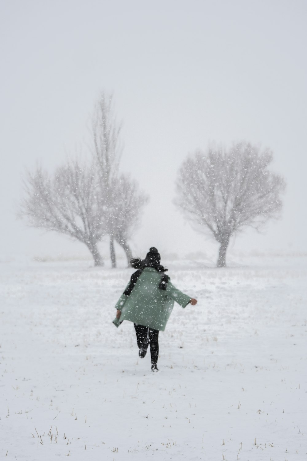 a woman walking through a snow covered field