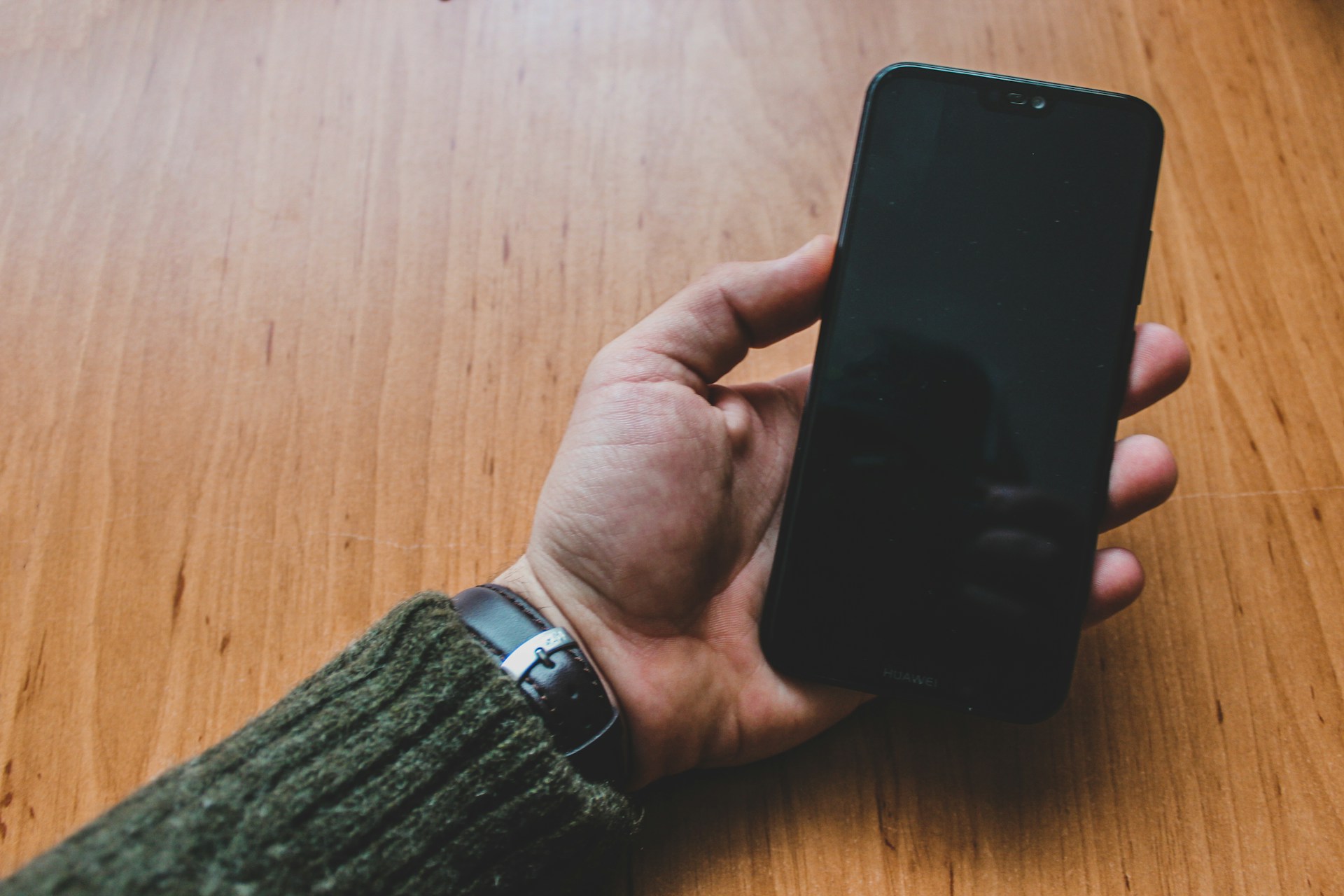 a person holding a smart phone on a wooden table