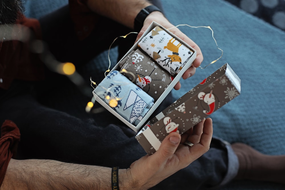 a person holding a small box with a christmas decoration on it